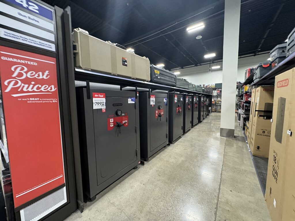 A row of various gun safes displayed for sale in a retail store aisle.