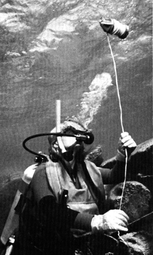 Black-and-white archive photograph of Dave Parker underwater holding the line to a diving float.