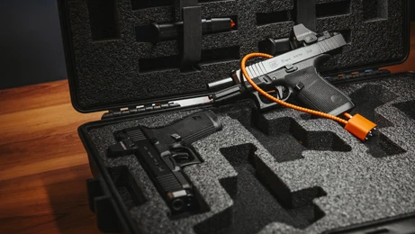 GLOCK press photograph of a pistol secured with an orange cable lock in an open protective case.