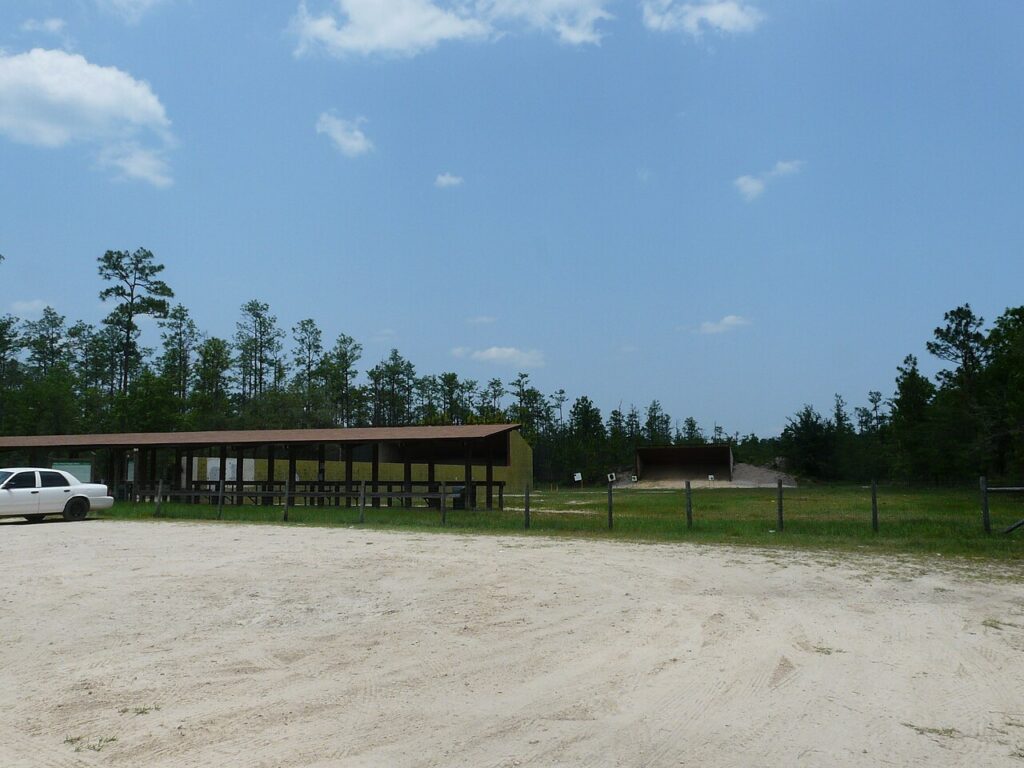 An outdoor public shooting range with a covered firing line structure and open field.