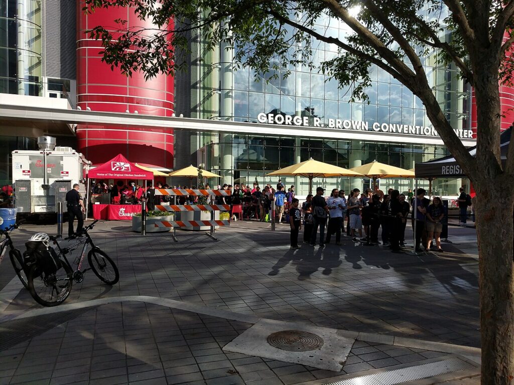 Exterior view of the George R. Brown Convention Center with attendees gathering near the entrance.