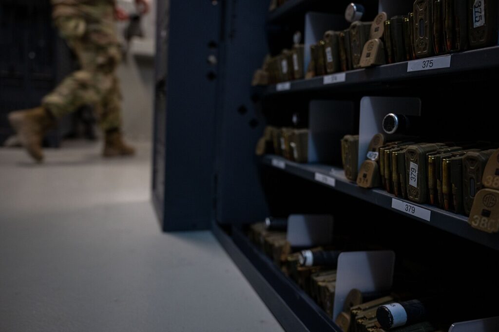Rows of organized magazines in a storage rack at an armory, emphasizing structured equipment management.