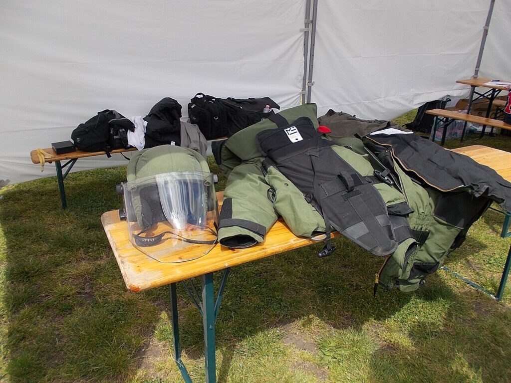 Tactical protective helmet and gear suit laid out on a wooden table at an outdoor exhibition.