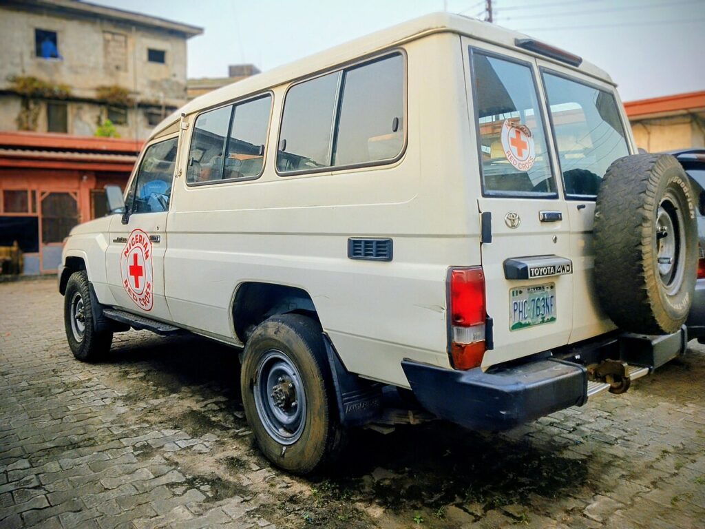 A white off-road vehicle with a red cross emblem, representing a mobile logistics and emergency unit.
