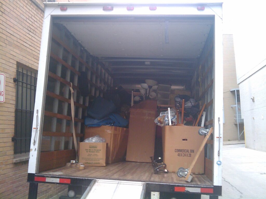 The open interior of a moving truck filled with various cardboard boxes and equipment for transport.